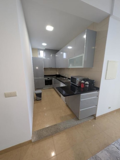 Cozinha moderna no Apartamento Sol e Mar das Villas Eden, com armários cinza, bancada preta e aço inoxidável
