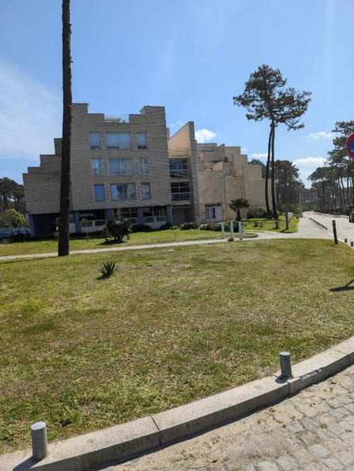Edifício de pedra moderno no hotel rural Villas Eden em Fão, com gramado bem cuidado, pinheiros altos e área de pátio sob céu azul