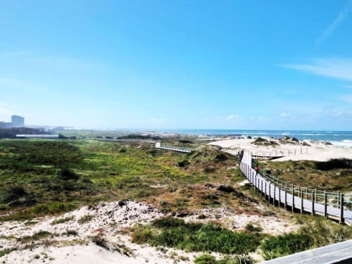 Paisagem de dunas costeiras em Villas Eden Fão com passadiço branco, praia arenosa e vista do Oceano Atlântico turquesa
