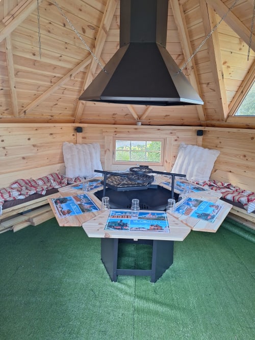 Intérieur cosy de cabane glamping en bois à La Cour d'Hortense avec foyer, espaces détente et grandes fenêtres