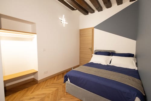 Chambre moderne ATHEA Appartements Paris avec lit queen-size, poutres apparentes, art géométrique et parquet