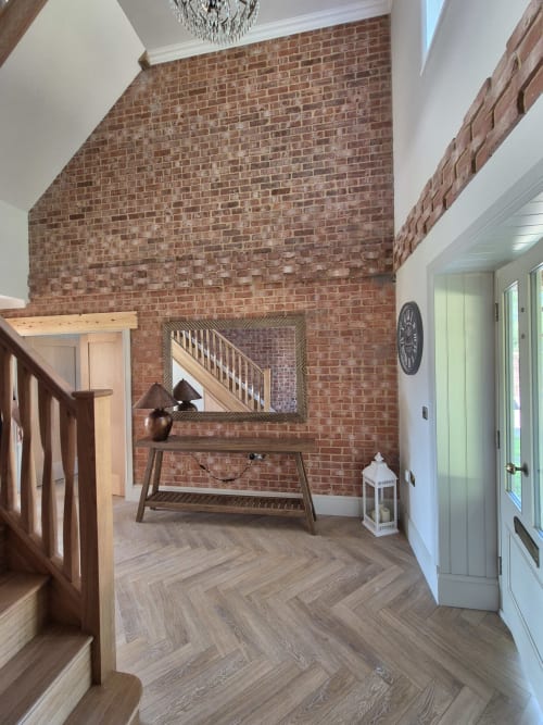 Modern hallway at Willy Mansion cottage in Fakenham with exposed brick wall, wooden staircase, and herringbone flooring