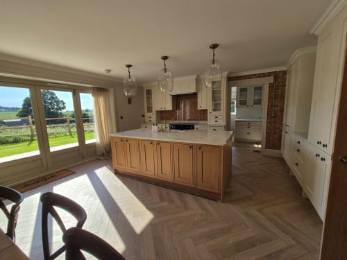 Modern kitchen with wooden island, cream cabinets, pendant lights, and garden views at Willy Mansion cottage in Fakenham