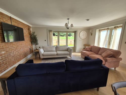 Spacious living room with multiple sofas at Villy Mansion cottage in Fakenham, garden views through patio doors