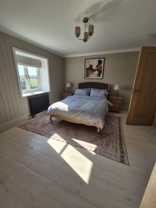 Bright bedroom at Rose Vill Homes cottage in Fakenham with wooden bed, blue bedding, hardwood floors, and garden view window