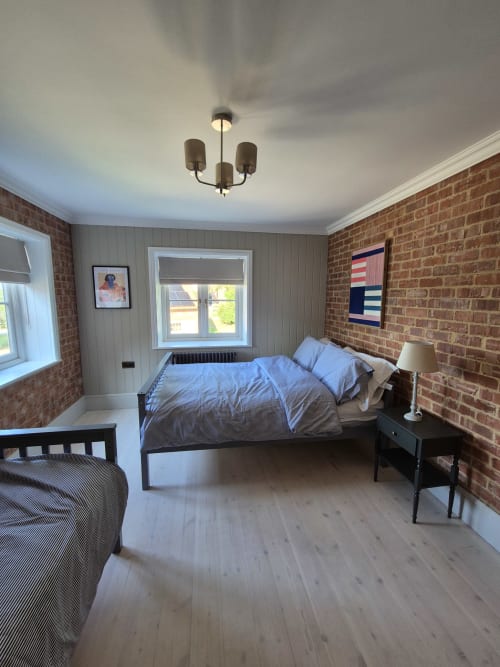 Spacious bedroom at Rose Vill Homes cottage in Fakenham with brick walls, two beds, wooden floors, and garden view windows