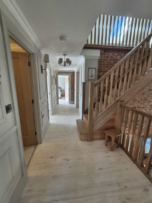 Spacious hallway with wooden staircase, hardwood floors, and brick wall at Willy Mansion cottage in Fakenham
