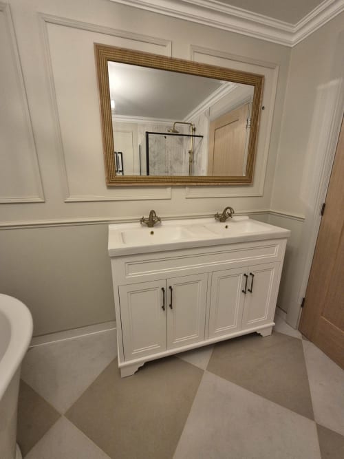 Elegant dual-sink bathroom vanity with white cabinetry and gold-framed mirror at Rose Vill Homes cottage in Fakenham
