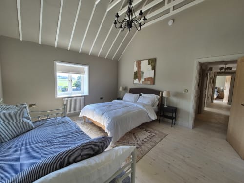 Spacious bedroom at Rose Vill Homes cottage in Fakenham with two beds, vaulted ceiling, chandelier, and garden views through