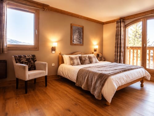 Chambre de luxe avec lit en bois, fauteuil et vue sur les montagnes aux Étoiles de la Plagne, Belle Plagne