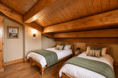 Chambre douillette avec poutres en bois, deux lits aux couvertures vertes et vue sur la montagne aux Étoiles de la Plagne, Belle Plagne
