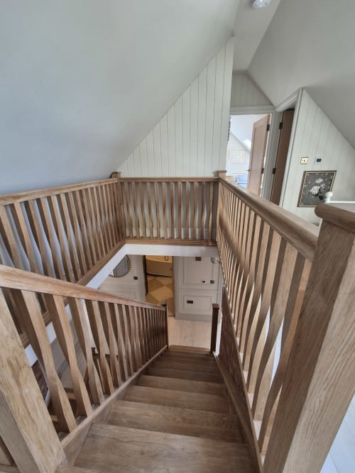 Wooden staircase with railings at Villy Mansion cottage in Fakenham, connecting two levels with white walls and hardwood