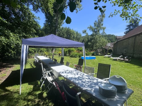 Jardin extérieur du Clos du Buisson avec auvent bleu, tables de salle à manger et vue sur la campagne à Saint-Aubin-sur-Gaillon.