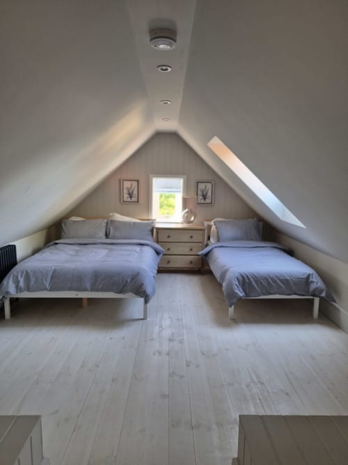 Twin bedroom in attic room at Rose Vill Homes cottage, Fakenham with blue bedding and window garden view