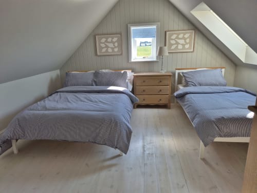 Attic bedroom with two twin beds, blue striped bedding, wooden furniture, and garden views at Rose Vill Homes cottage in