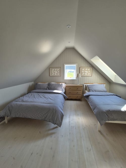 Bright attic bedroom at Rose Vill Homes cottage in Fakenham with two twin beds, wooden dresser, and sloped ceiling