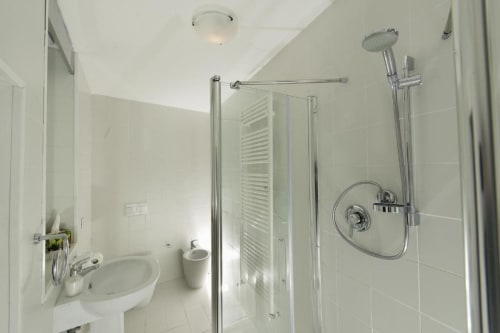 Baño moderno en el B&B del Podestà de Fabriano con ducha abierta, lavabo de pedestal y azulejos blancos