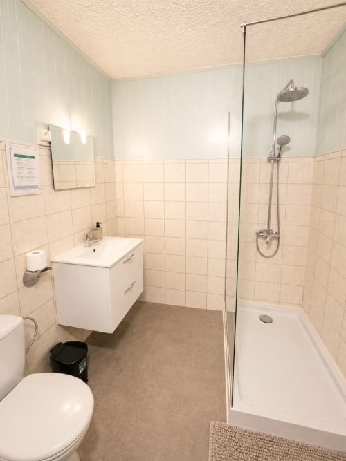 Salle de bain moderne avec douche à l'italienne, vasque blanche et toilettes à l'Hôtel Les Alizés au Pouzin