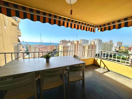 Balcón soleado de apartamento frente al mar en Picanya con mesa de comedor, vista al Mediterráneo y toldo rayado