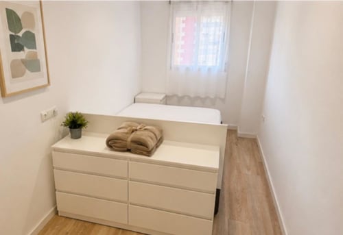 Dormitorio moderno con cómoda blanca, planta decorativa y toallas en ML Apartments, apartamento frente al mar en Picanya