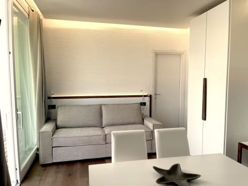 Modern apartment living area at Like at Home Palau with gray sofa, dining table, and white chairs in bright contemporary