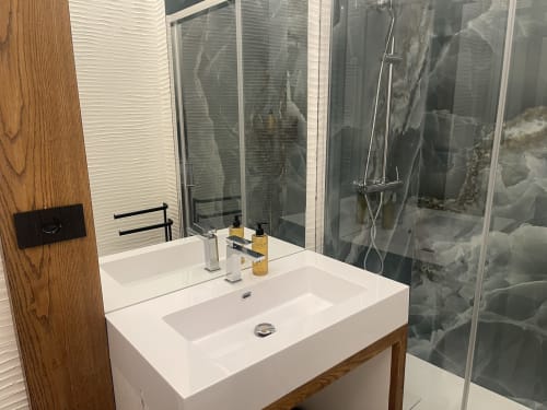 Modern bathroom vanity with white sink, wooden cabinet, and glass shower enclosure at Like at Home Palau apartment, Palau