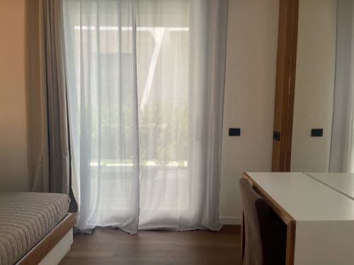 Modern apartment bedroom with garden view, sheer curtains, wooden furniture, and private patio access at Like at Home Palau
