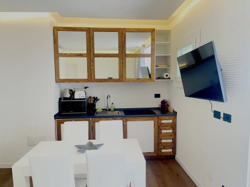 Modern kitchenette in Palau apartment with wooden cabinets, wall-mounted TV, and dining area
