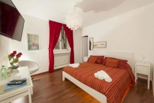 Cozy red bedroom at B&B del Podestà in Fabriano with orange striped bed, white furniture, and city views