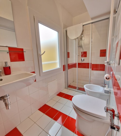 Bagno moderno con piastrelle rosse e bianche, doppio lavabo e doccia walk-in al B&B del Podestà a Fabriano