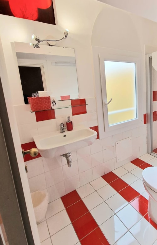Bagno moderno rosso e bianco alla Camera Rossa del B&B del Podestà, Fabriano con lavabo, specchio e pavimento piastrellato