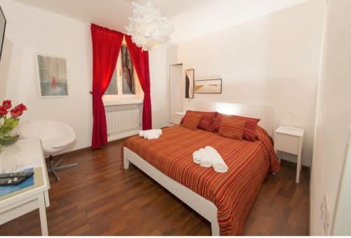 Camera Camera Rossa del B&B del Podestà a Fabriano con letto a righe rosse, tende rosse e pavimenti in legno