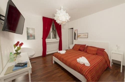 Camera luminosa al B&B del Podestà a Fabriano con biancheria a righe rosse, arredi bianchi, tende rosse e vista sulla città