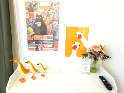 Arredamento della camera Oro al B&B del Podestà a Fabriano con statuette di uccelli gialli, fiori freschi e quadri colorati su sfondo bianco