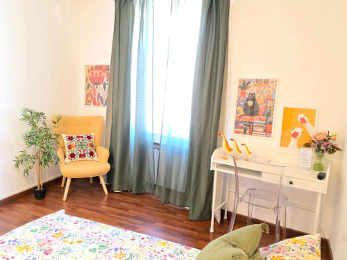 Camera luminosa nella B&B del Podestà di Fabriano con sedia gialla, scrivania bianca, opere d'arte colorate e vista sulla città