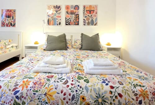 Bright bedroom at B&B del Podestà in Fabriano with floral bedding, green pillows, and colorful botanical artwork above the