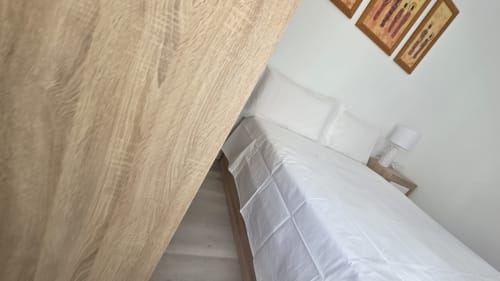 Ropa de cama blanca en cama de cabaña frente al mar en MONICA SOCARICI, Oropesa, con suelo de madera y decoración de pared