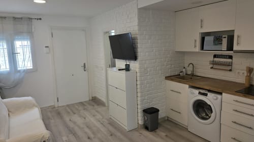Cocina y sala de estar cottage moderna en Benicàssim con ladrillos blancos, cocina equipada, lavadora, TV y madera