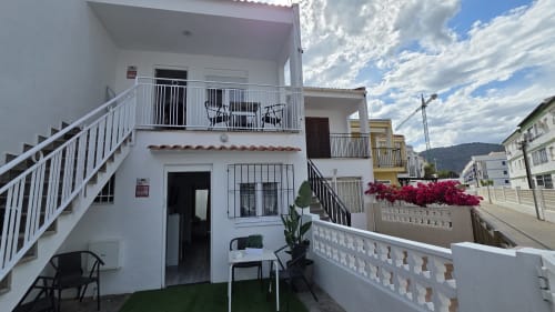 Terraza de la casa Monica Socarici en Benicàssim con barandillas blancas, muebles de jardín, flores y vistas a las montañas