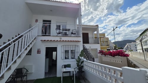 Apartamento-villa blanco frente al mar en Benicàssim con balcones, vista al jardín y flores de buganvilia rosa