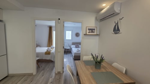 Comedor moderno en Monica Socarici, Benicàssim, con mesa de madera, acceso a cocina y vistas al dormitorio