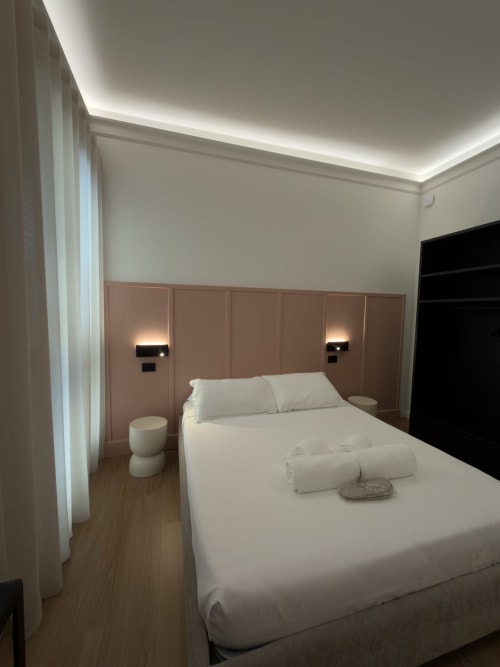 Camera moderna a Maison Riviera con biancheria bianca, testiera tortora, illuminazione ambientale al soffitto e pavimenti in legno a Reggio