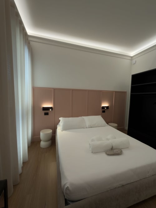 Camera moderna a Maison Riviera, Reggio di Calabria - letto matrimoniale con biancheria bianca, testata beige, luci ambientali a soffitto