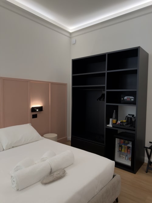 Camera matrimoniale moderna a Maison Riviera, Reggio di Calabria, con letto bianco, testata rosa, mensole nere e