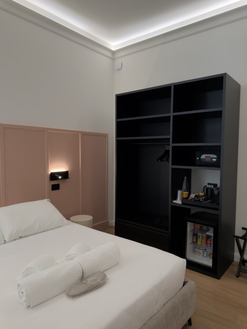 Camera Essenza matrimoniale a Maison Riviera a Reggio di Calabria con letto, scaffalatura nera e illuminazione moderna