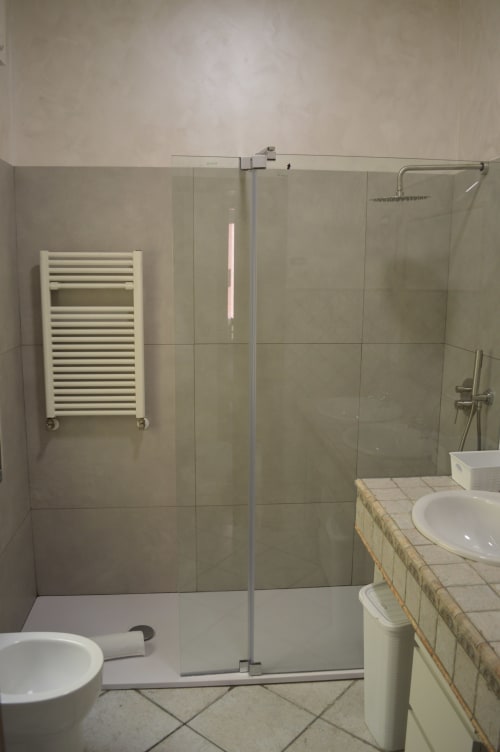 Bagno moderno a ViOletta Lido di Ostia con doccia walk-in, scaldasalviette bianco e lavabo vanity