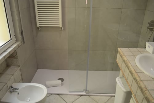 Bagno moderno dell'Hotel ViOletta, Lido di Ostia, con box doccia in vetro, lavabo bianco e scaldasalviette