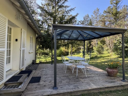Shaded patio with dining table at Domaine de Bize Mirepoix, featuring pergola roof and garden views in Ariège, France