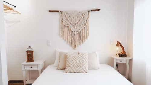 Quarto moderno na Vila Vale Guest House com parede de macramé, roupa de cama branca e detalhes em madeira em Charneca da Caparica