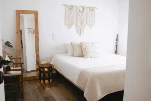 Bright Land Suite bedroom at Vila Vale Guest House with white bed, macramé wall hanging, wooden mirror, and neutral decor